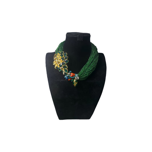 Handcrafted multistrand emerald green seed beads statement necklace from the Opus collection with  bold green and gold toned focal piece surrounded by a cluster of corals, agates and crystals, shown on  a mannequin