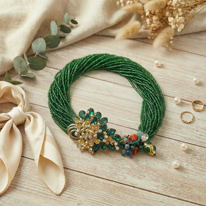 Emerald green multistrand seed bead statement necklace on a wooden surface with decorative elements.